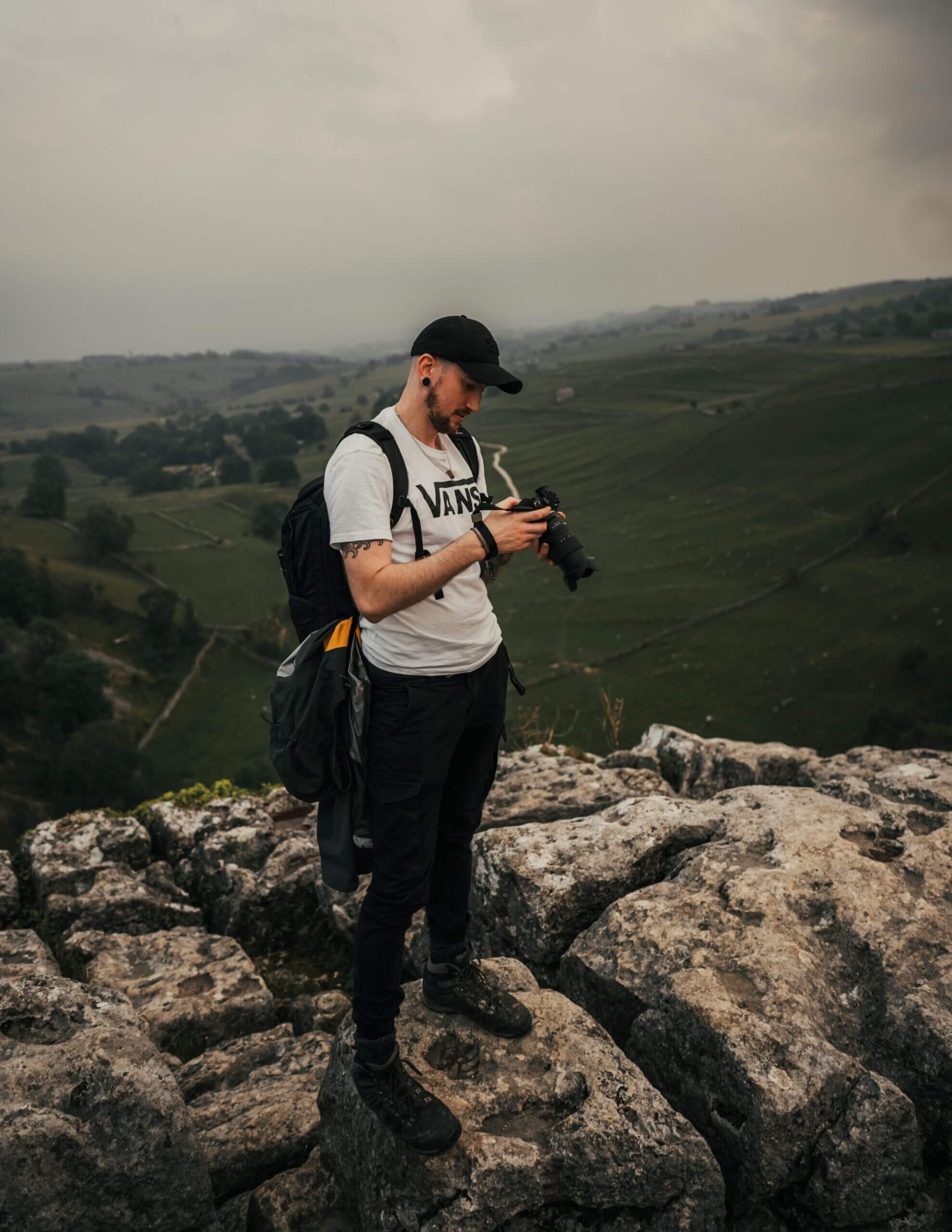 Man in White T-Shirt and Black Pants Holding Black Dslr Camera